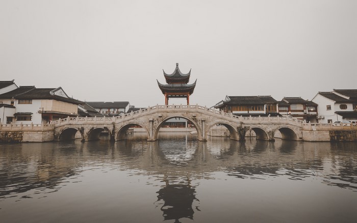 Stone bridge with Chinese architecture over water