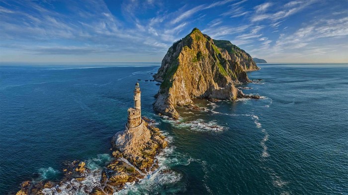 Lighthouse on rocks near island in the sea