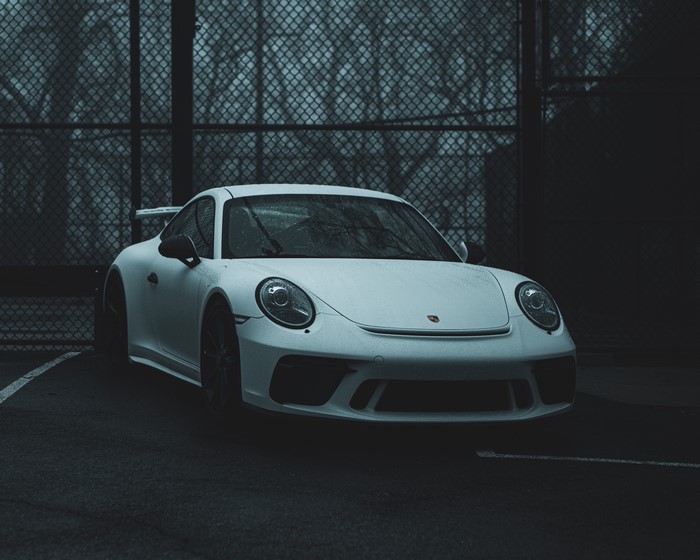 White Porsche 911 GT3 parked near a fence
