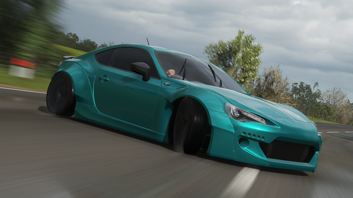 Teal Toyota drifting on a road