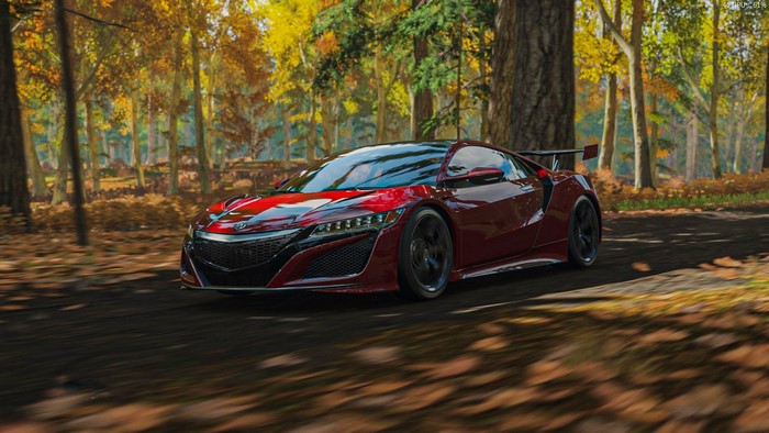 Red Acura NSX driving on a forest road in autumn