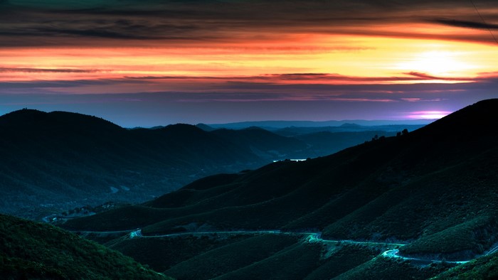 Mountain road at sunset with colorful clouds