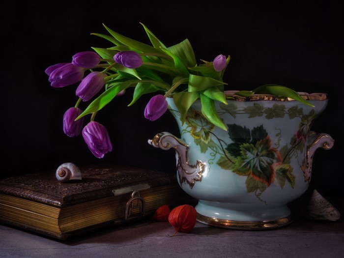 Purple tulips in a decorative vase on a book