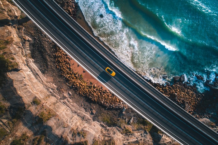 Yellow car driving on a coastal road
