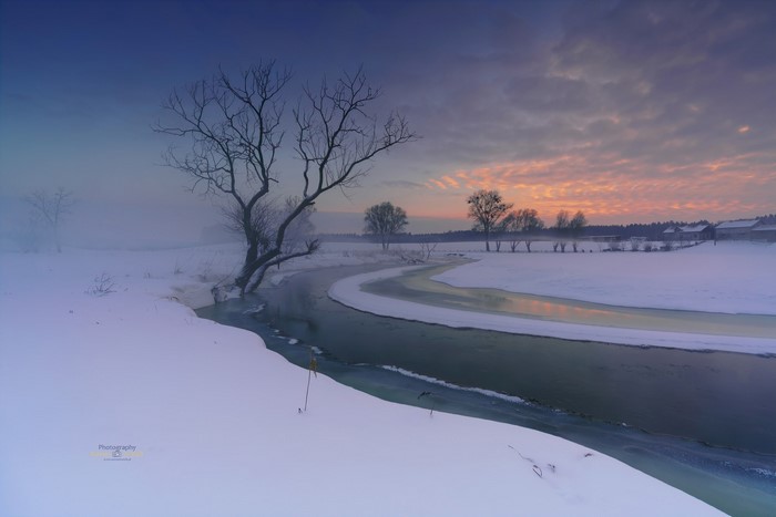 Winter sunset over a snowy landscape with a river