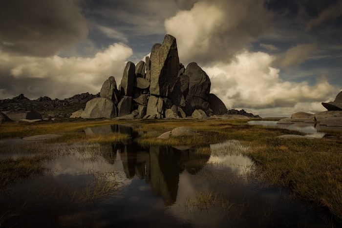 Rocky outcrop reflected in water under cloudy sky