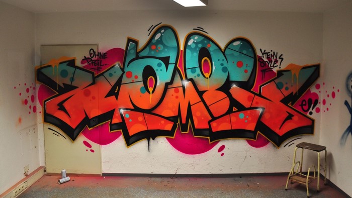 Graffiti artwork on a wall with a stool and spray cans