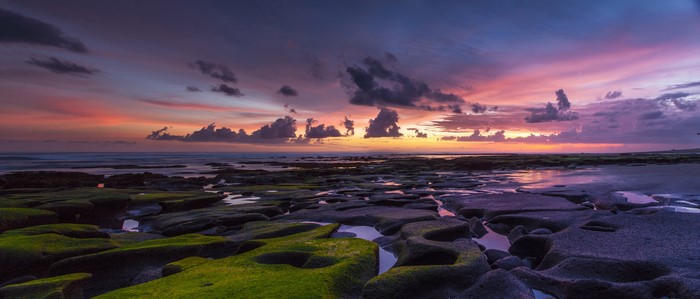 Sunset over rocky coast with colorful clouds