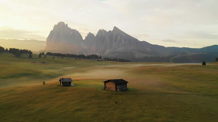 Mountain landscape with cabins and fog at sunrise