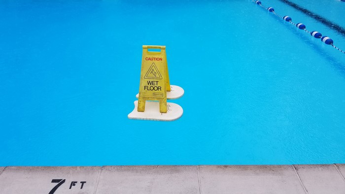 Wet floor sign floating in a swimming pool