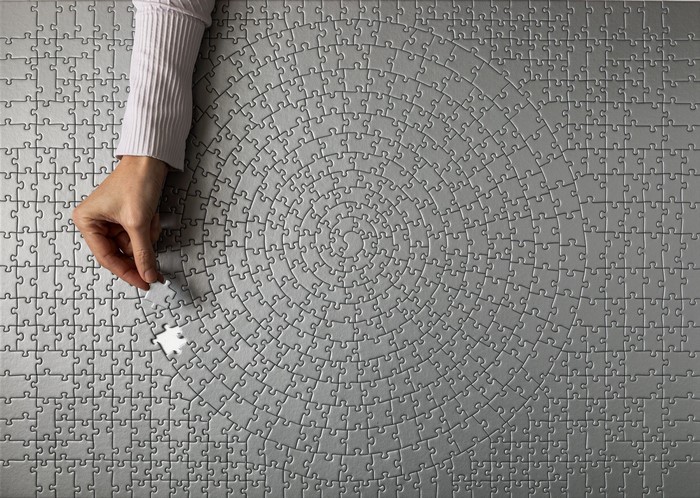 Hand placing a puzzle piece on a circular puzzle