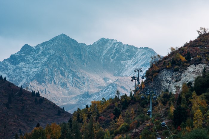 Cable cars ascend a mountain with snow-capped peaks