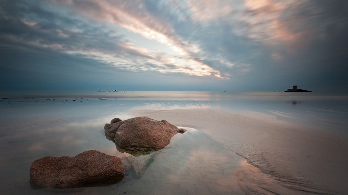 Beach with rocks and a distant tower