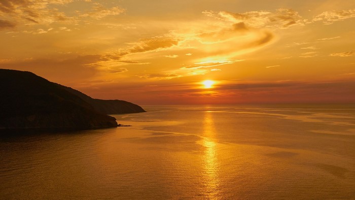 Sunset over the ocean with a coastal mountain range