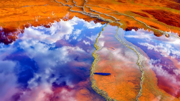 Orange and blue water with cloud reflections