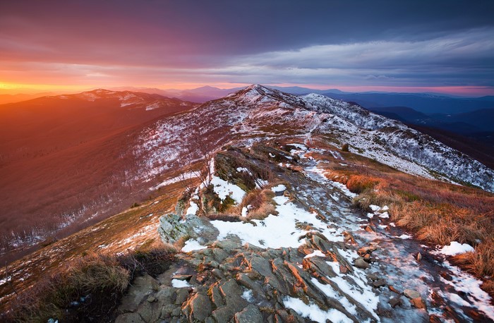 Snowy mountains at sunset with dramatic sky