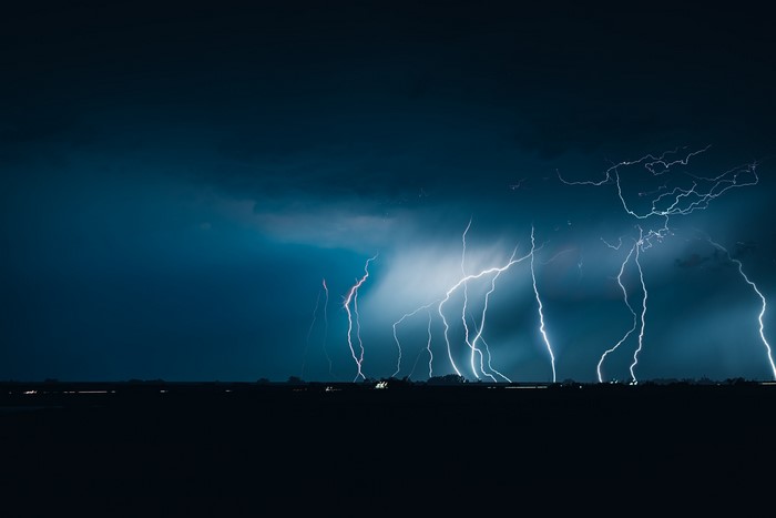 Lightning strikes over a dark landscape at night
