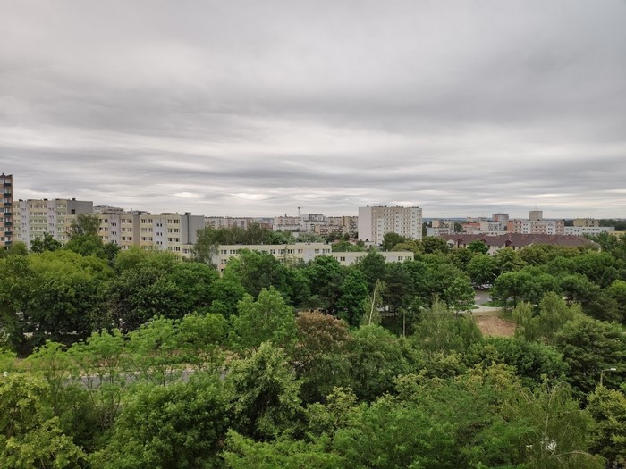 Apartment buildings and trees under a cloudy sky