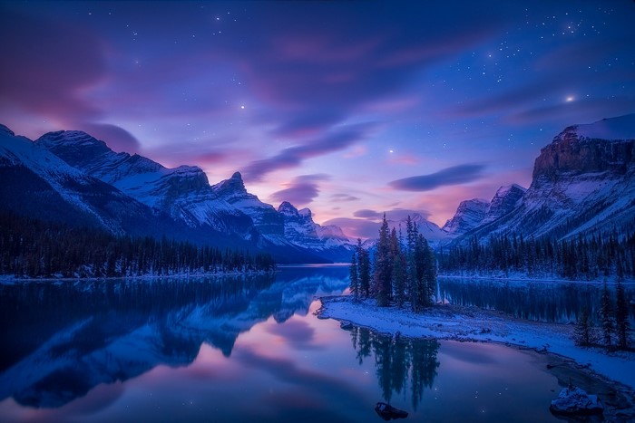 Snowy mountains and lake at night with stars