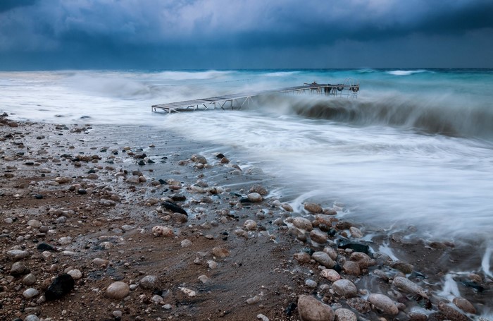 Wooden pier on a rocky beach with crashing waves