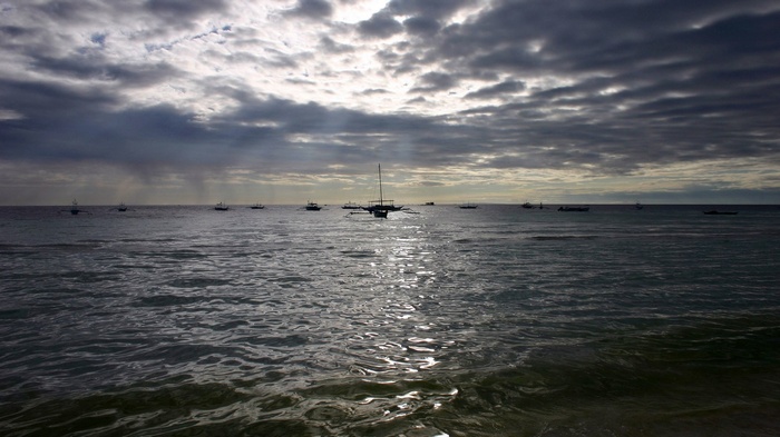 Boats on the ocean under a cloudy sky