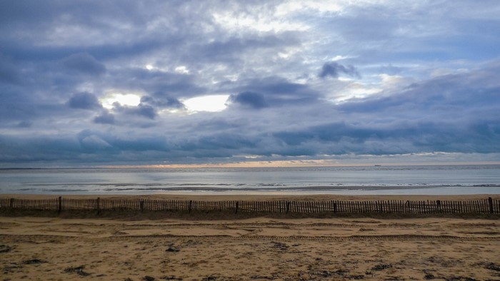 Beach with wooden fence and cloudy sky