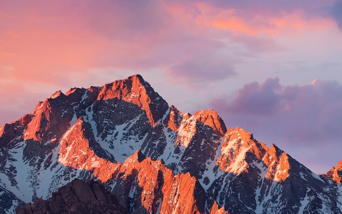 Snow-capped mountains at sunset with pink clouds