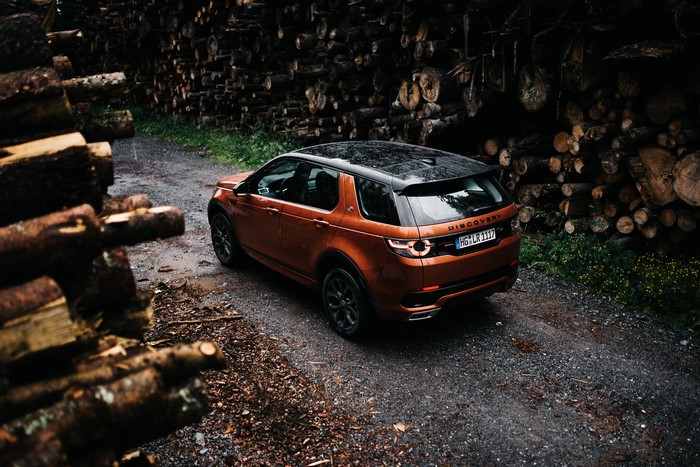 Orange Land Rover Discovery Sport on a wet forest road