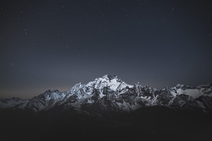 Snow-capped mountains under a starry night sky