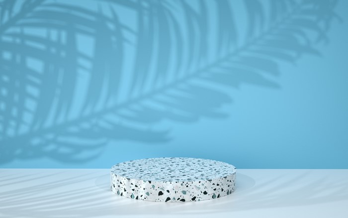 Terrazzo podium with palm leaf shadows on blue background