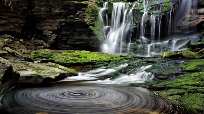 Waterfall cascading over mossy rocks into a swirling pool