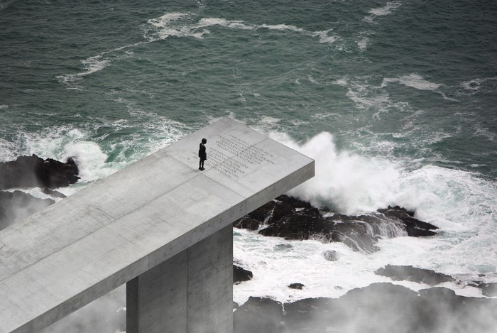 Modern concrete structure overlooking stormy ocean waves