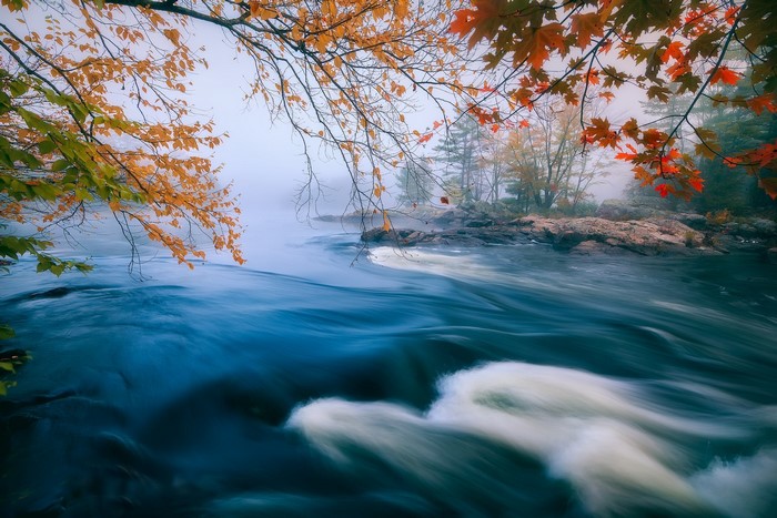 River flowing through rocks with fall foliage and mist