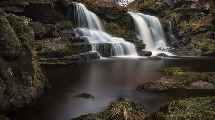 Waterfall cascading over mossy rocks into a dark pool