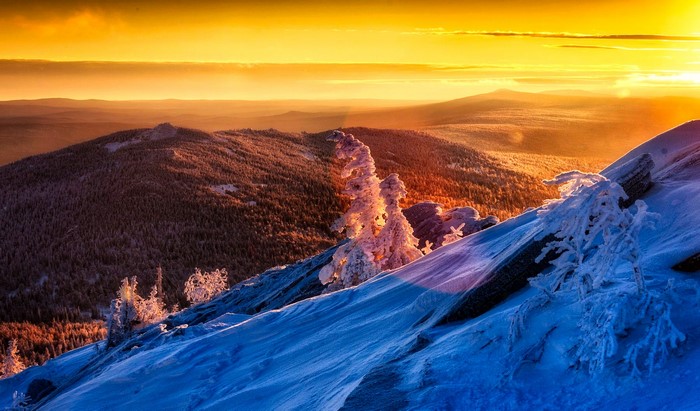 Winter sunset over snow-covered mountains and forests