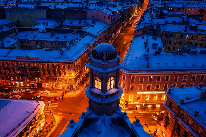Snowy cityscape at night with people and cars