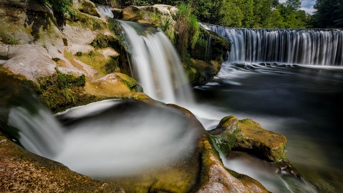 Waterfalls cascading over mossy rocks in a forest