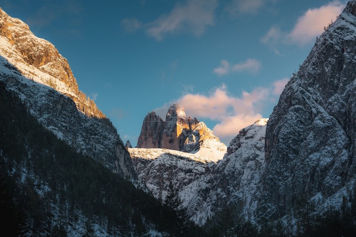 Snowy mountains with trees and clouds