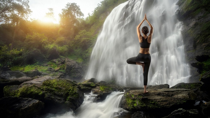 Woman doing yoga in front of a waterfall