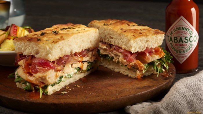 Chicken sandwich with Tabasco sauce on cutting board