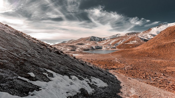 Snowy mountains and lake under cloudy sky