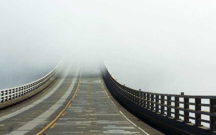 Road on a bridge disappearing into fog