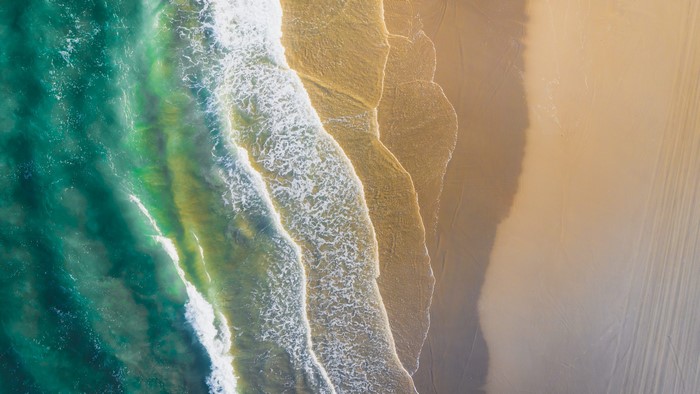 Aerial view of ocean waves crashing on a sandy beach