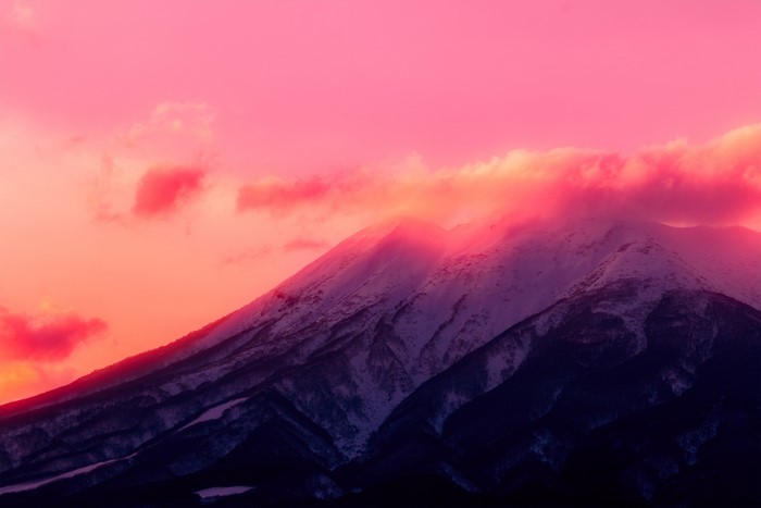 Snow-capped mountains at sunset with pink clouds