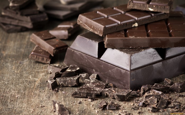 Dark chocolate bars and pieces on wooden surface