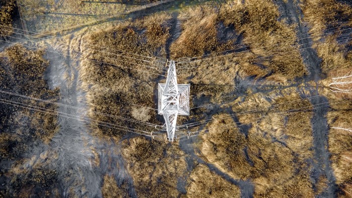 Aerial view of power lines and pylon over dry grass