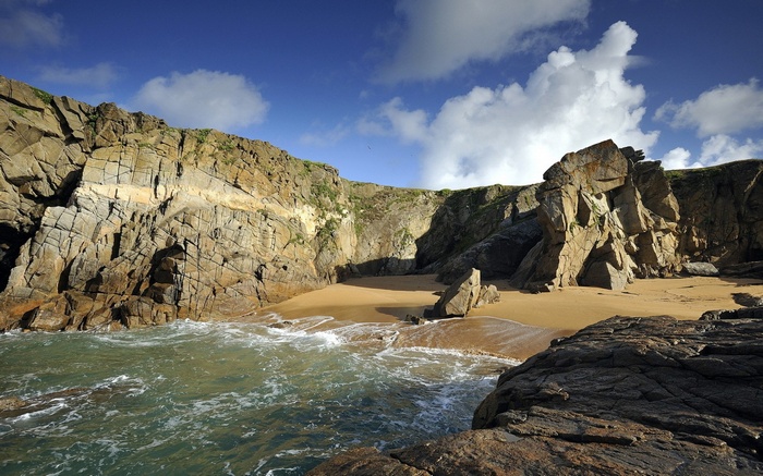 Rocky cove with sandy beach and blue sky