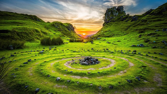 Spiral stone circle at sunset in a grassy valley