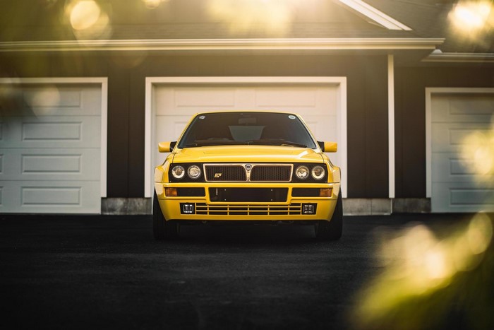 Yellow Lancia Delta Integrale in front of a garage