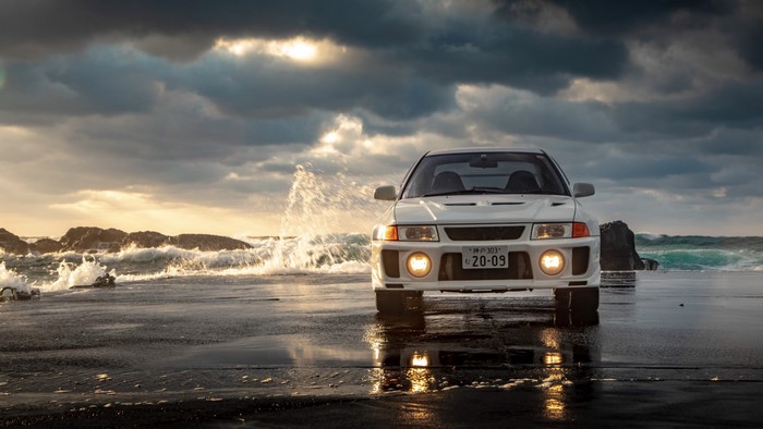 White Mitsubishi Lancer Evo V on a beach with waves